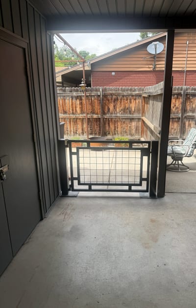 Black steel pedestrian gate with mesh infill panel.